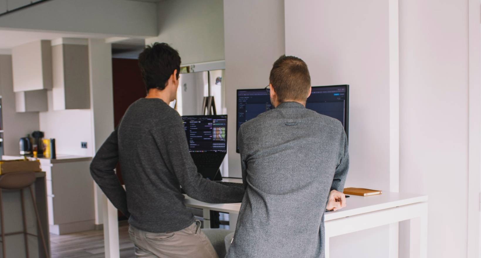 Twee medewerkers van Mad IT poseren voor hun Audi bedrijfswagens voor het hoofdkantoor met Mad IT-logo - softwarebedrijf gespecialiseerd in .NET en Microsoft-technologie met focus op innovatie, teamwork en aangename werksfeer.